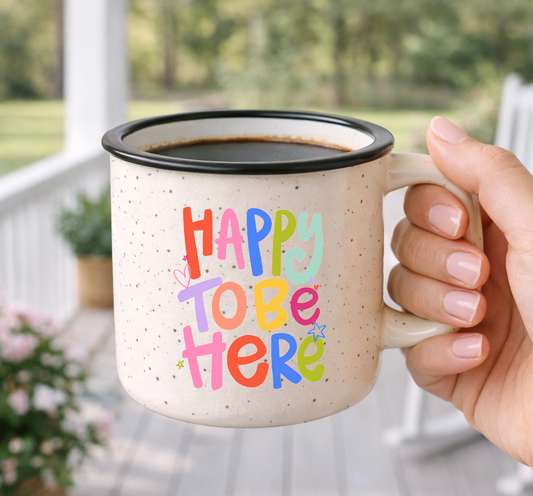 Doodles by Rebekah "Happy To Be Here" inspirational campfire mug. This whimsical hand-painted ceramic coffee cup features vibrant typography and is an ideal gift for positive home decor, daily encouragement, or as a cheerful addition to a farmhouse-style kitchen.