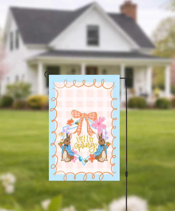 Doodles by Rebekah "Hello Spring" garden flag featuring whimsical hand-painted rabbits and an orange checkered bow. This charming Easter and spring-themed outdoor decor, with its peach checkered pattern and blue border, is perfect for front yards or garden displays.
