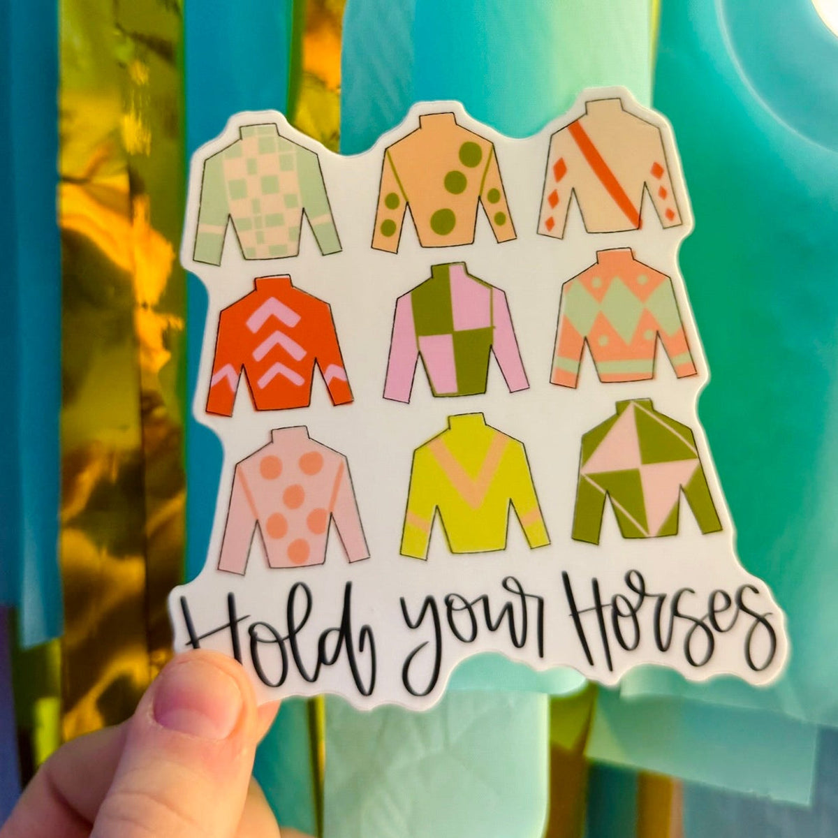 Doodles by Rebekah "Hold Your Horses" equestrian-themed vinyl sticker. This colorful hand-painted decal featuring colorful jockey silks is a perfect gift for horse lovers and racing fans to decorate water bottles, laptops, and planners.