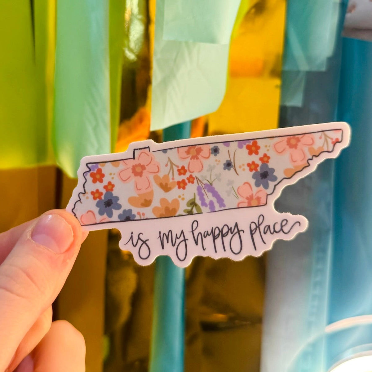 Doodles by Rebekah "Tennessee is my happy place" floral state sticker. This whimsical hand-painted vinyl decal features a botanical Tennessee map design, making it a perfect gift for Tennessee residents or a cheerful souvenir for decorating water bottles, laptops, and planners.