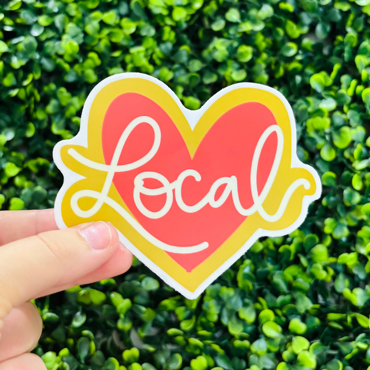 A hand holding a Local Red Heart Sticker
