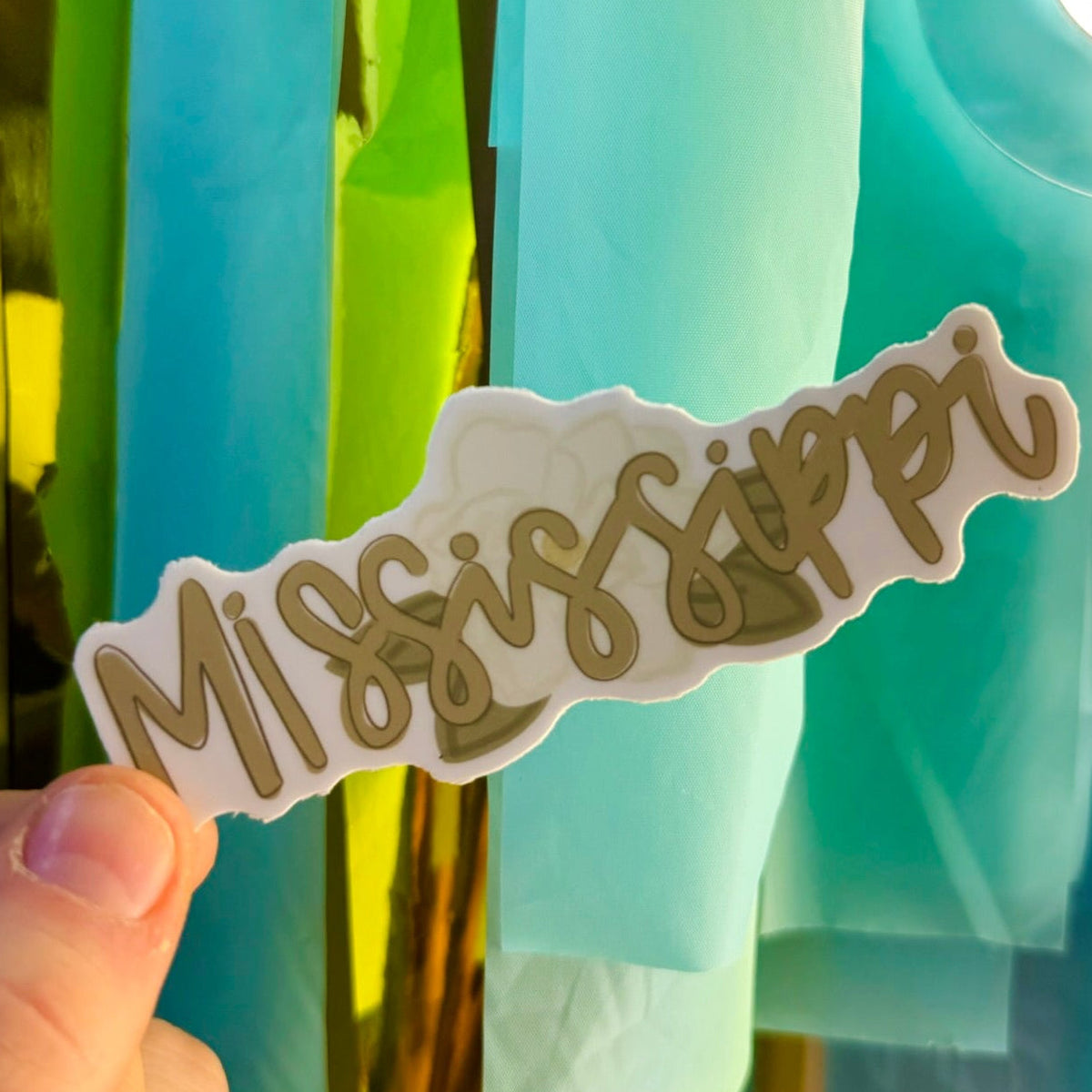 Doodles by Rebekah Mississippi floral state pride sticker. This whimsical hand-painted decal featuring the state flower magnolia and elegant script is a perfect gift for Mississippians to decorate water bottles, laptops, and planners.
