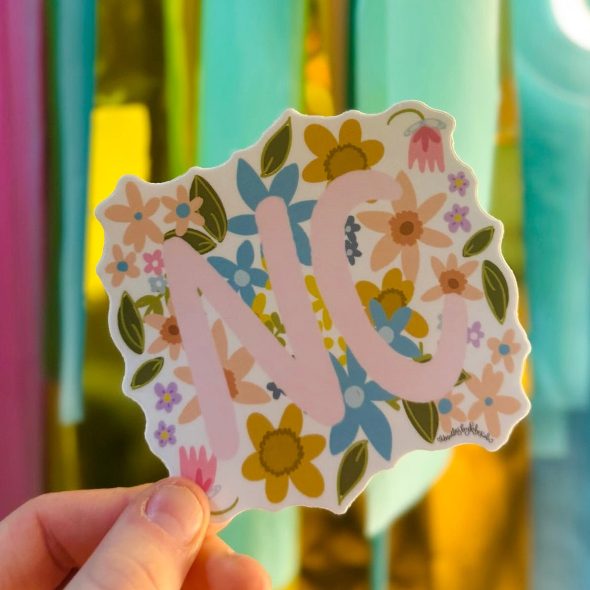 Doodles by Rebekah North Carolina "NC" state pride floral sticker. This whimsical hand-painted vinyl decal with botanical accents and pink lettering is a perfect gift for North Carolinians to decorate water bottles, laptops, and planners.