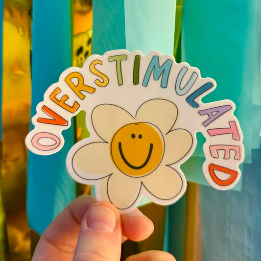 Doodles by Rebekah "Overstimulated" whimsical smiley flower sticker. This colorful hand-painted vinyl decal with a daisy illustration is a relatable gift for neurodivergent individuals and mental health awareness, perfect for decorating water bottles, laptops, and planners.