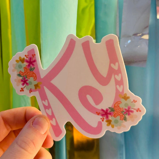 Doodles by Rebekah floral Kentucky (KY) state abbreviation sticker. This whimsical pink monogram vinyl decal features hand-painted botanical details and hearts, making it a perfect state pride gift for decorating water bottles, laptops, and planners.