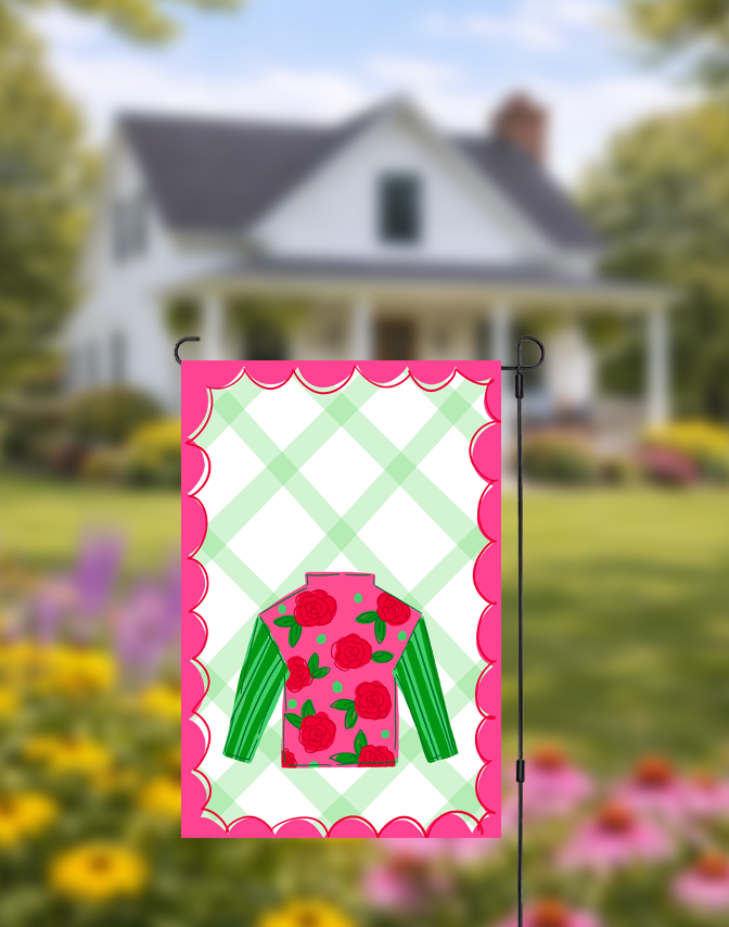 Decorative garden flag with a green and pink design in front of a house and garden.