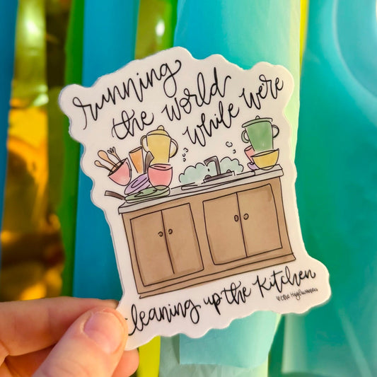 Doodles by Rebekah "Running the World" kitchen-themed motivational sticker. This colorful hand-painted vinyl decal with a sink and dishes illustration is a relatable and empowering gift for mothers and homemakers to decorate laptops, planners, and refrigerators.