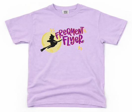 Lavender t-shirt with a witch graphic and 'Frequent Flyer' text on a white background
