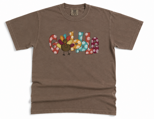 Brown t-shirt with colorful 'Gobble' design on a white background