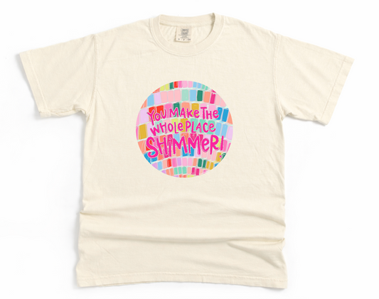 Beige t-shirt with colorful graphic and text on a white background