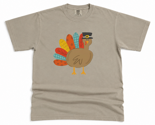 Beige t-shirt with a colorful turkey graphic on a white background