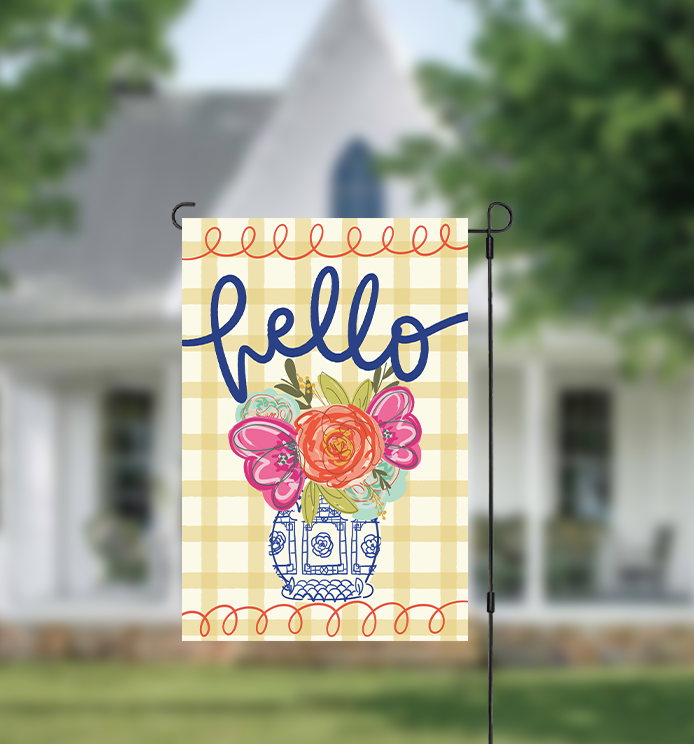 Decorative garden flag with floral design and 'hello' text in front of a house.