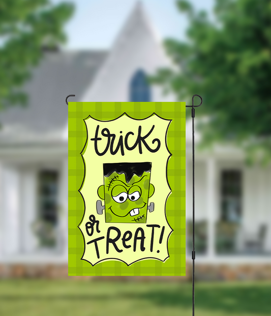 Halloween-themed garden flag with a cartoon character and 'Trick or Treat!' text in front of a house.
