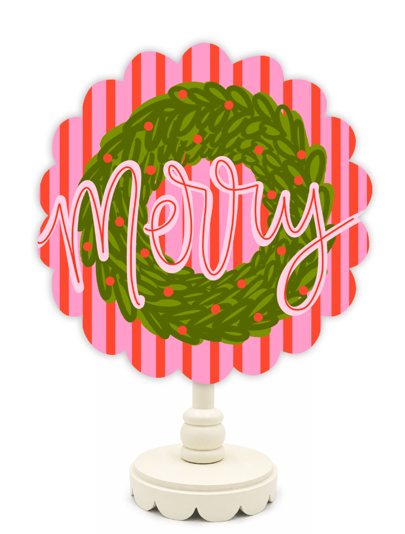 Decorative sign with 'Merry' and a Christmas wreath design on a pink and red striped background.