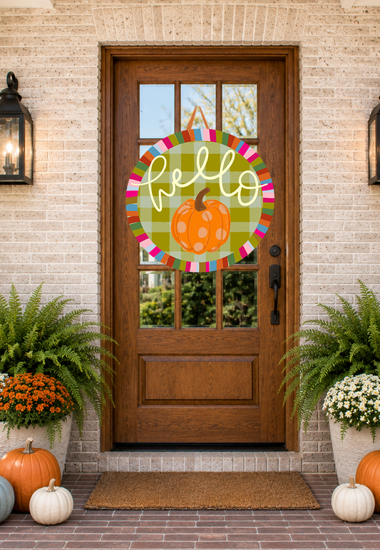 Front door with a decorative 'hello' sign featuring a pumpkin, flanked by potted plants and pumpkins on a brick patio.
