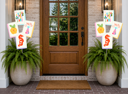 Decorative signs with colorful designs on a door with potted plants on either side.