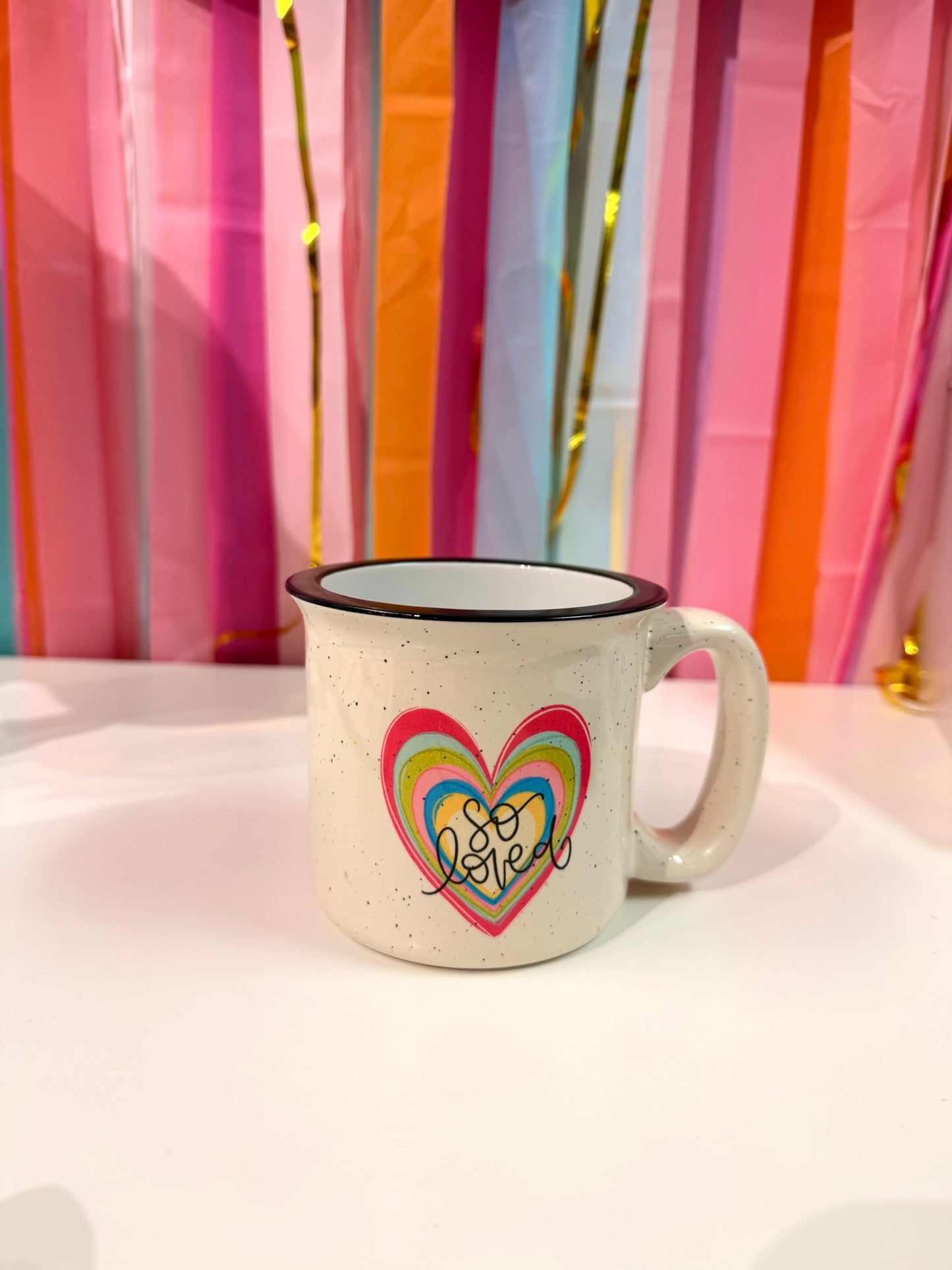 Doodles by Rebekah "So Loved" heart campfire mug featuring a colorful, hand-painted layered heart design. This whimsical ceramic coffee cup makes a thoughtful Valentine's Day gift, birthday present, or a sweet daily reminder of being loved.