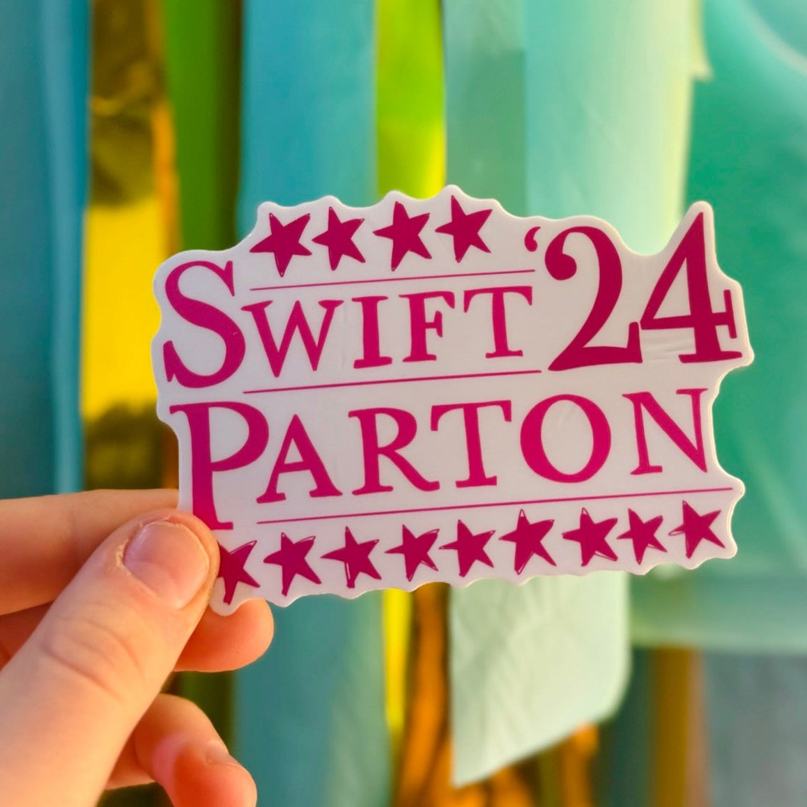 Doodles by Rebekah "Swift Parton '24" Taylor Swift and Dolly Parton campaign-style sticker. This pink whimsical vinyl decal is a perfect pop-culture gift for music fans to decorate water bottles, laptops, and planners.