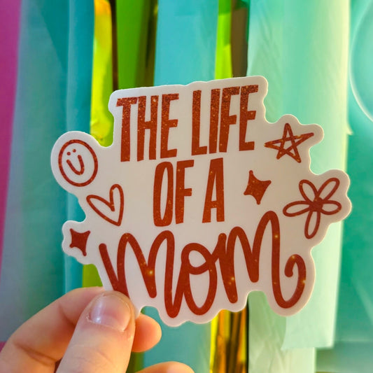 Doodles by Rebekah "The Life of a Mom" burnt orange glitter sticker. This whimsical hand-painted vinyl decal with sparkling typography is a perfect gift for Mother's Day or for decorating water bottles, laptops, and planners.