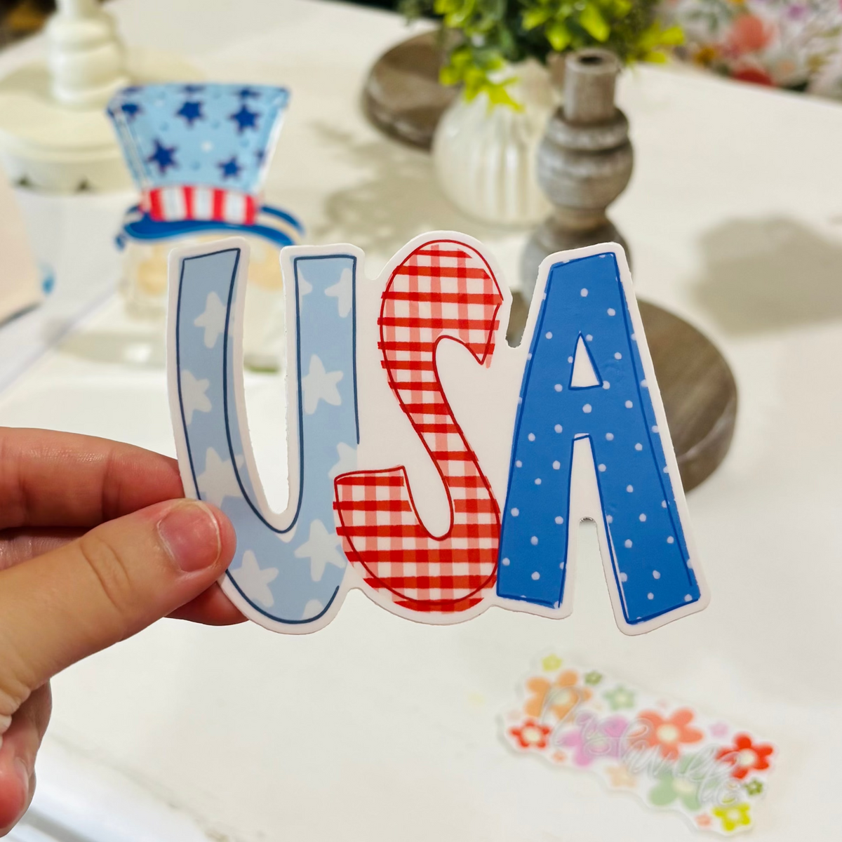 a hand holding a hand drawn sticker reading USA