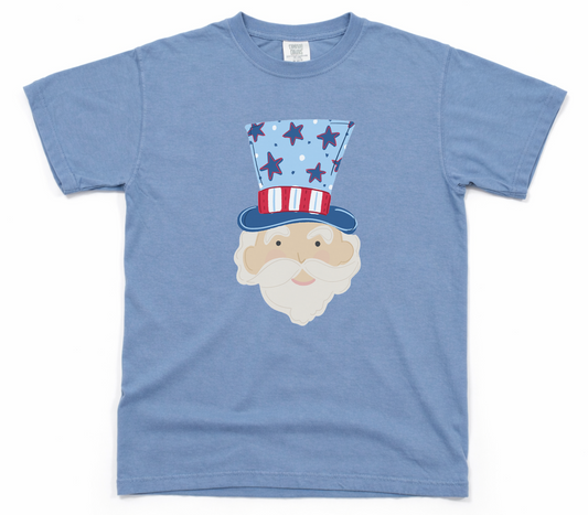 Blue t-shirt with a graphic of a face wearing an American flag hat on a white background