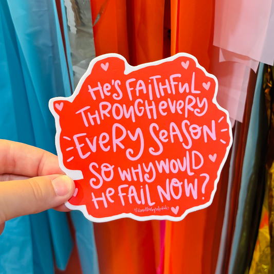 A hand holding a pink & red sticker that reads "He's Faithful Through Every Season So Why Would He Fail Now?"