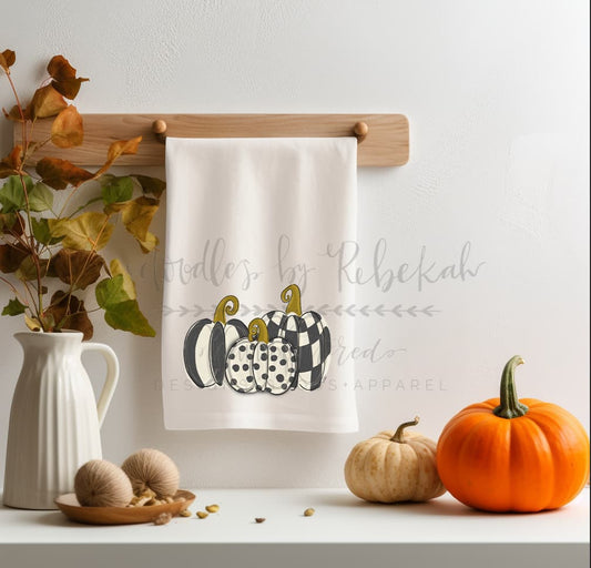 Whimsical fall tea towel with a black and white patterned pumpkin topiary illustration, perfect for autumn kitchen decor and Thanksgiving hosting gifts.