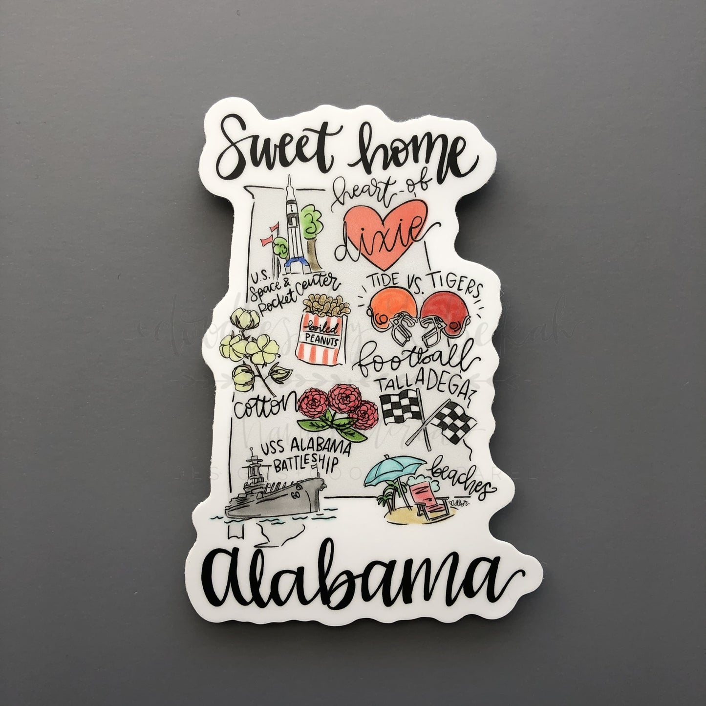 An Alabama map sticker that reads Sweet Home Alabama on a black background