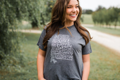 a smiling woman wearing a charcoal grey tee that has the state of Alabama on it