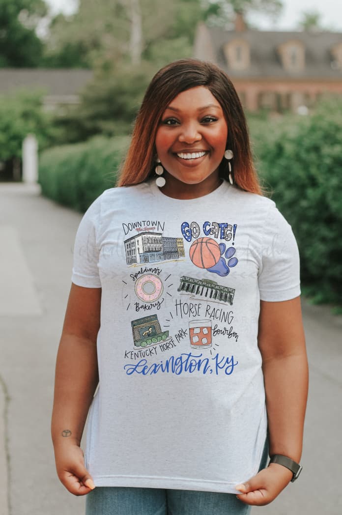 a woman standing wearing a white short sleeve tee with several hand drawn graphics on it representing Lexington, KY
