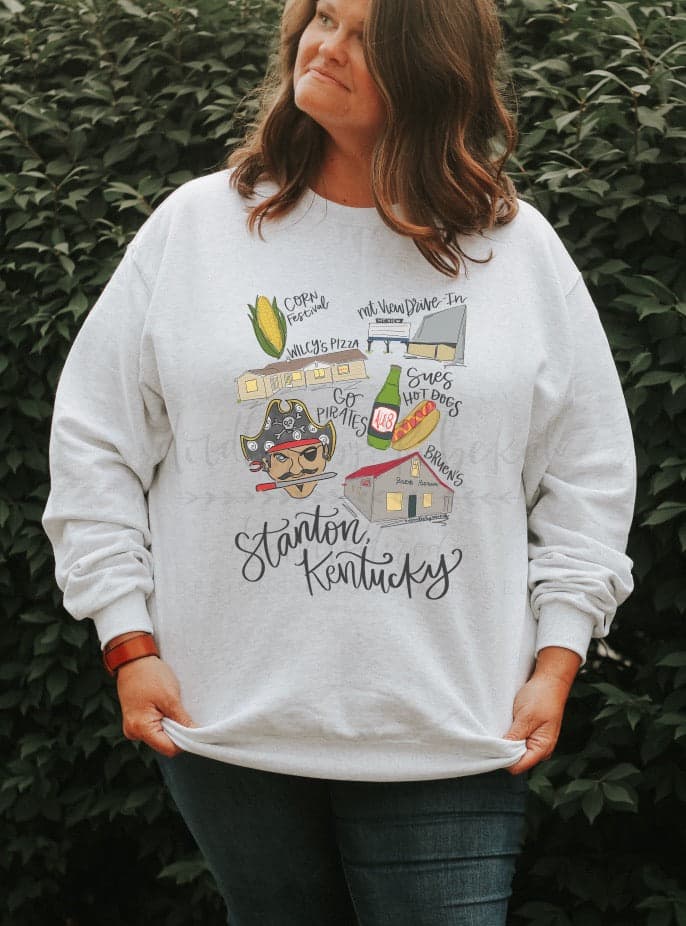 Woman wearing a white sweatshirt with doodles of Stanton, KY