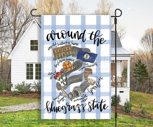 A garden flag with a blue and white checkered background featuring images of people, a basketball, and state-related symbols, with the text 'around the bluegrass state'.