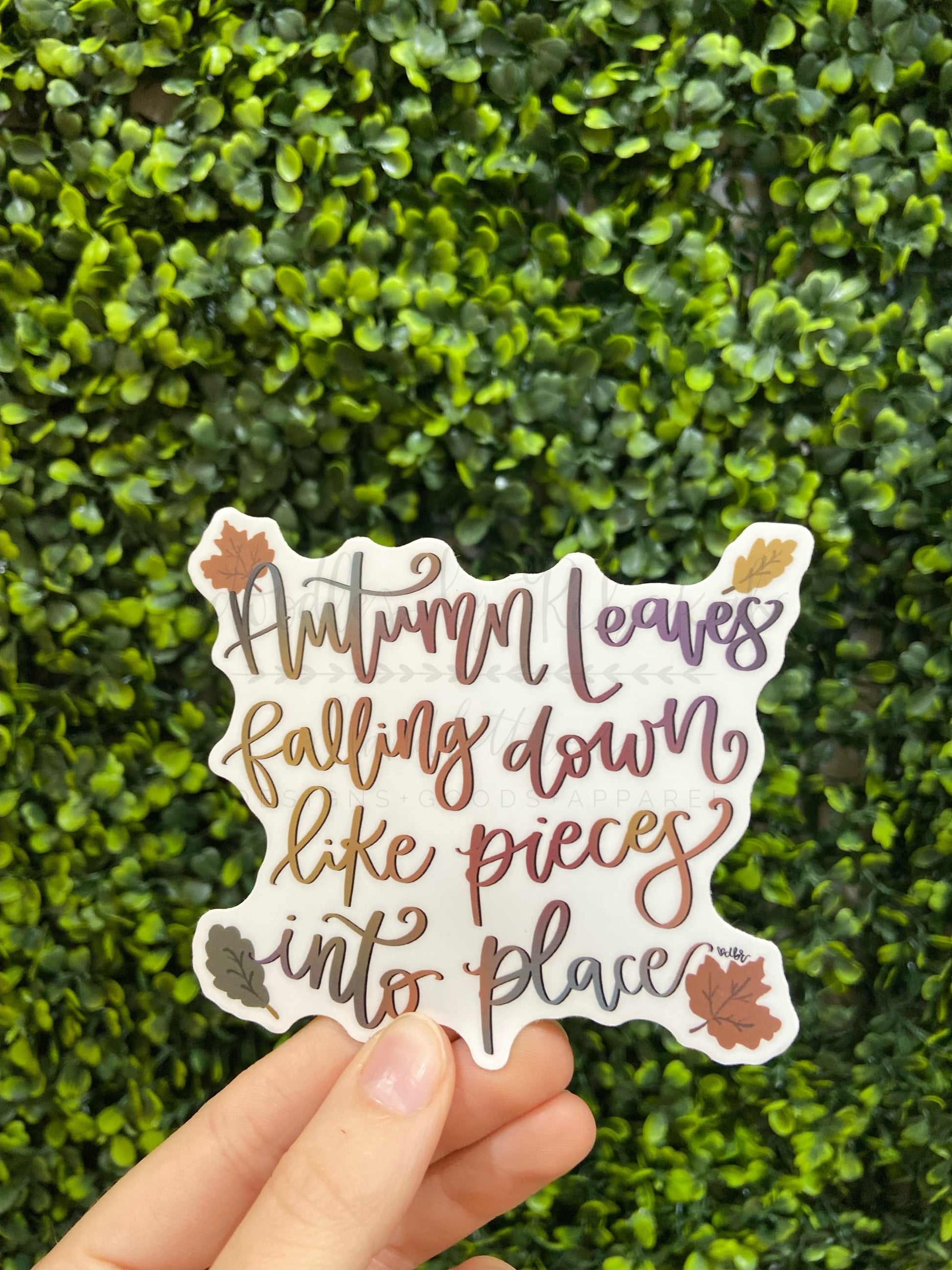 A sticker with a fall-themed design, featuring text that reads 'Autumn leaves falling down like pieces into place', surrounded by leaf illustrations in purple and gold colors.