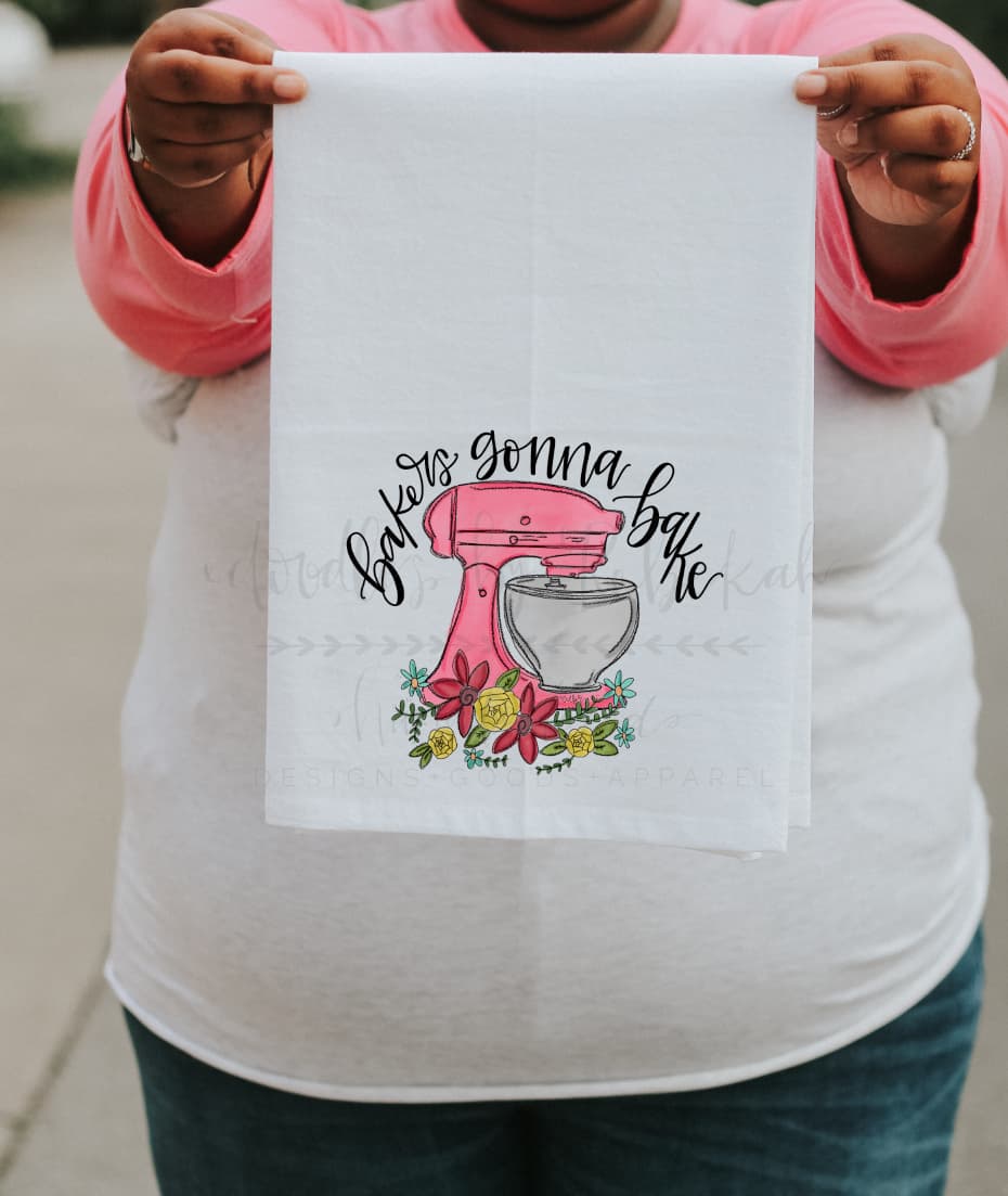 Person holding a white tea towel with a colorful design of a stand mixer