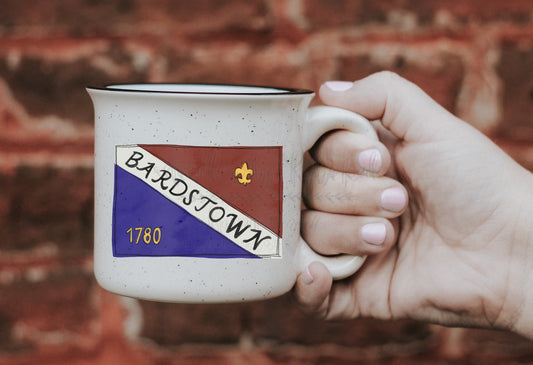 Person holding a coffee mug with flag of Bardstown