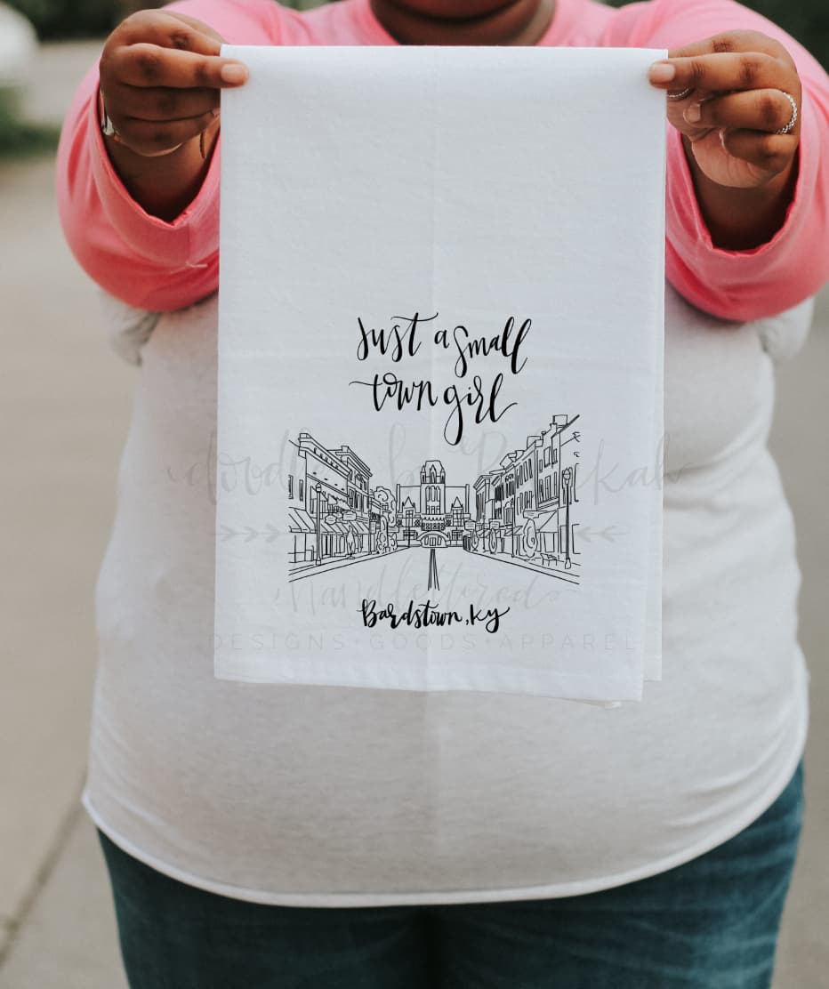 Woman holding a tea towel of a Bardstown, KY streetscape
