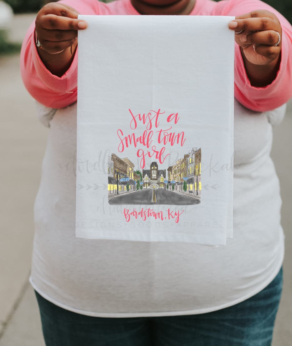 Woman holding a colorful tea towel with a doodle of Bardstown, KY