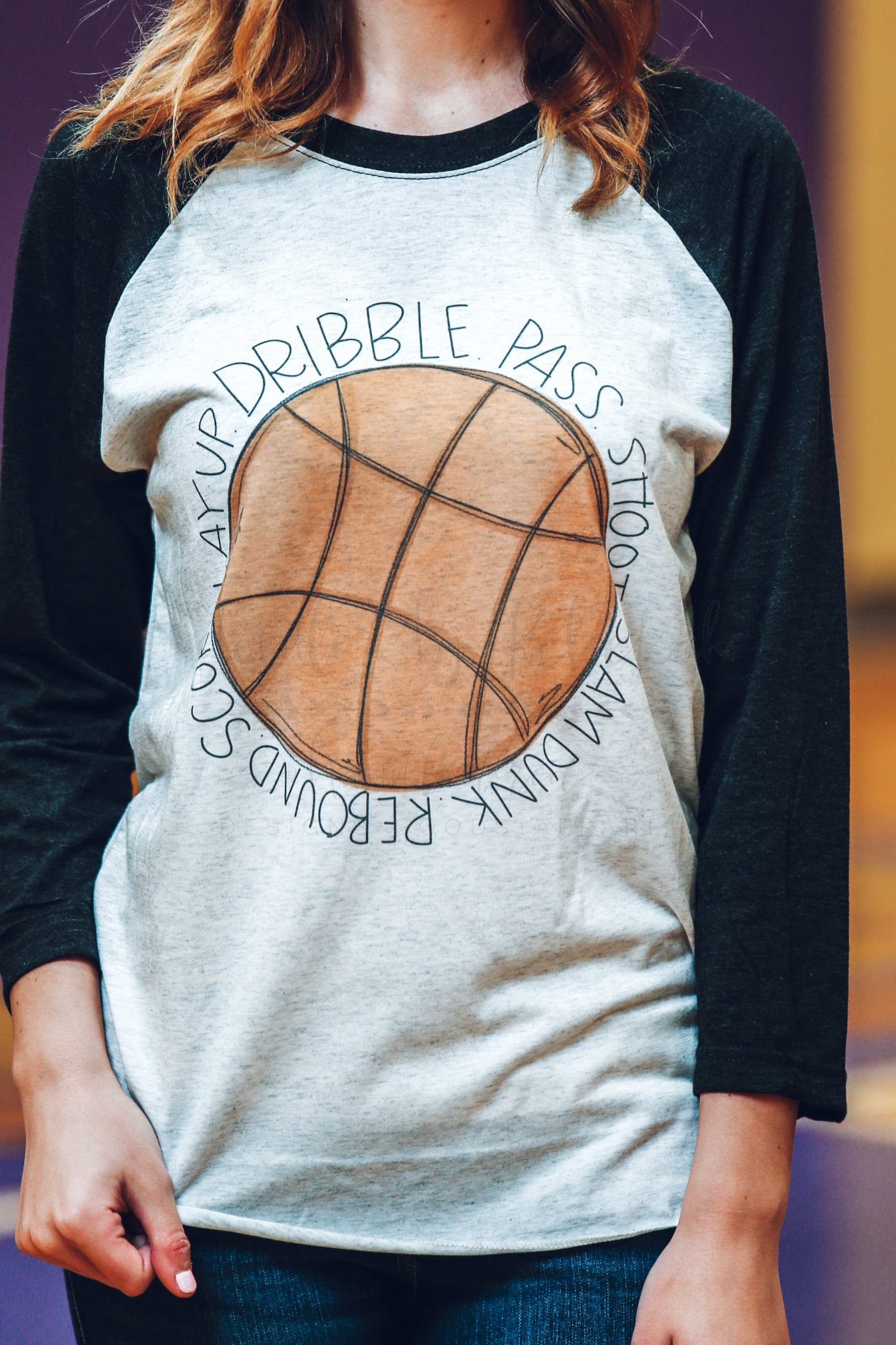 close up of a woman wearing a raglan t-shirt with a basketball graphic