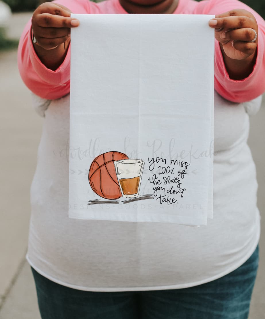 person holding a tea towel with a graphic of a basketball and shot glass
