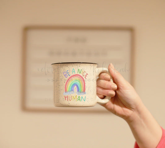 Person holding a coffee mug with graphic stating "Be a nice human"