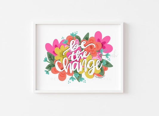 An 8x10 framable print featuring a colorful floral design with the phrase 'BE THE CHANGE' in a bold, cursive handwriting on a white background.