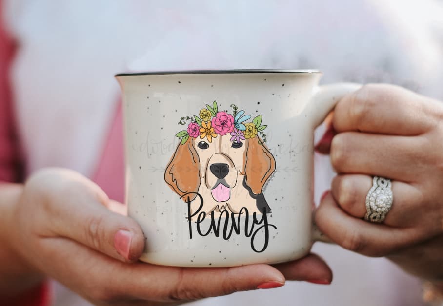 Person holding a coffee mug with a graphic of a female beagle with a flower crown and the name 'Penny' underneath