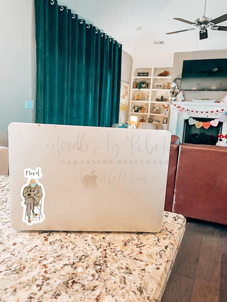 A sticker with a design applied to a laptop on a desk in a home environment, indicating the product is a sticker likely for personalizing devices.