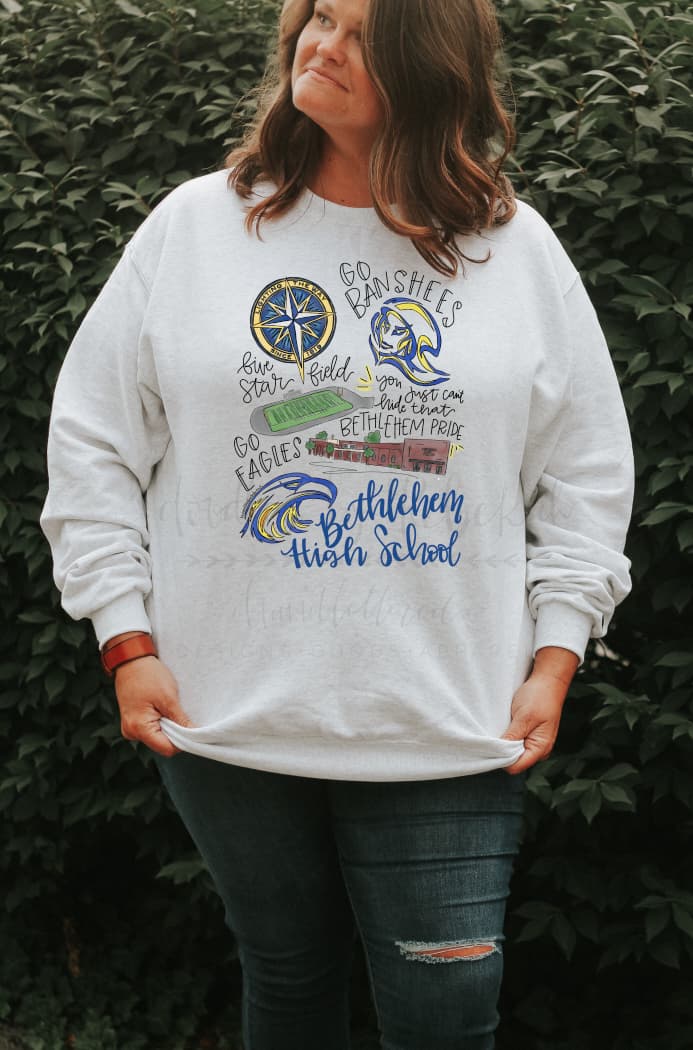 A person wearing a long-sleeved sweatshirt with white body, featuring hand-drawn lettering and designs related to Bethlehem High School.