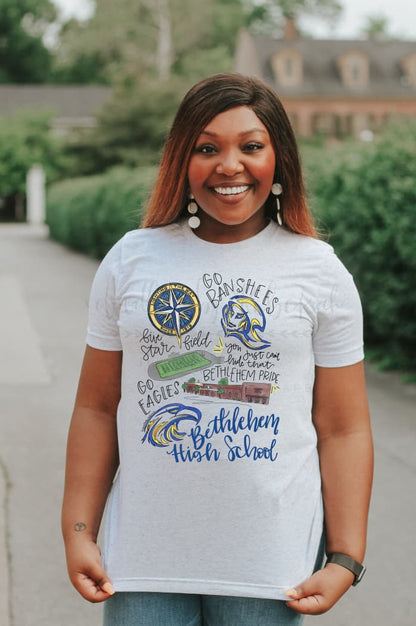 A person wearing a short sleeve tee with a white body, featuring hand-drawn lettering and designs related to Bethlehem High School.