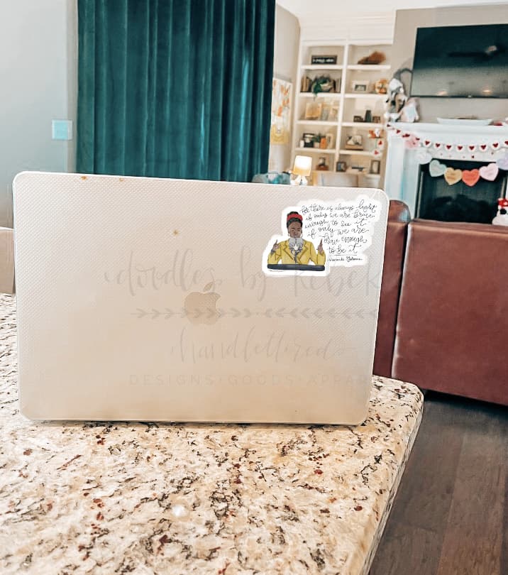 A sticker with a character illustration placed on a laptop, in a home setting.