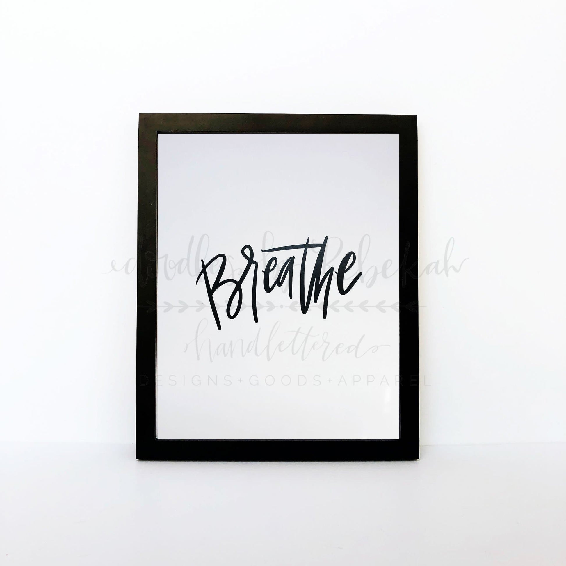 An 8x10 framable print with the word 'Breathe' in a cursive handwritten style font, predominantly in black color on a white background.