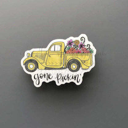 A sticker portraying a yellow truck with flowers in the back that says "gone pickin'"