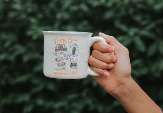 Person holding a white coffee mug with doodles of Tennessee