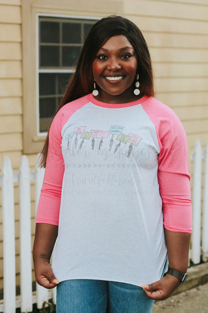 a woman wearing a pink and whit raglan that says "Your Voice Matters'